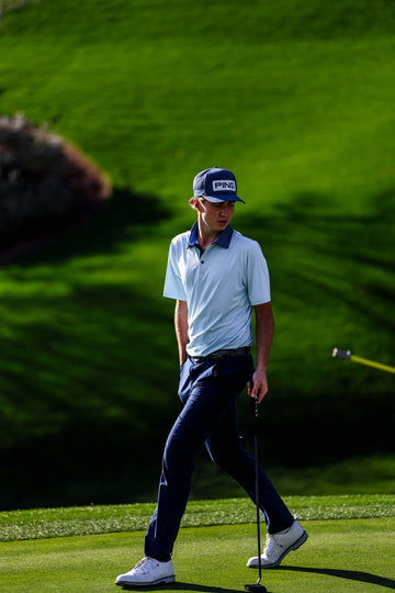 Golfer on a green golf course wearing a cap and white shirt.
